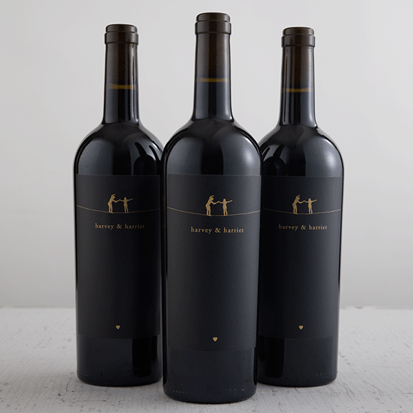 Three bottles of wine with black labels on a white background